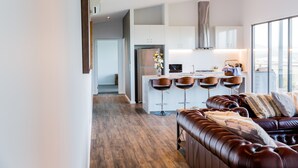 Een moderne keuken met witte kasten, een roestvrijstalen koelkast en een centraal eiland met barstoelen.