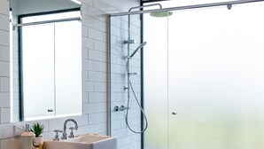 Een moderne badkamer met een douchecabine van glas, een witte wastafel en een grote spiegel.