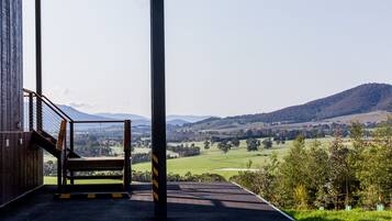 A covered outdoor area with a view of a green valley and hills.