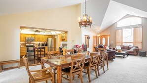 A spacious living area with a dining table and chairs, a sofa, and a kitchen in the background. - 🌲☀️Private Lakefront prop. with Kayaks, Paddle boards, boat rental PVT dock☀️🌲 (Twin Lakes)