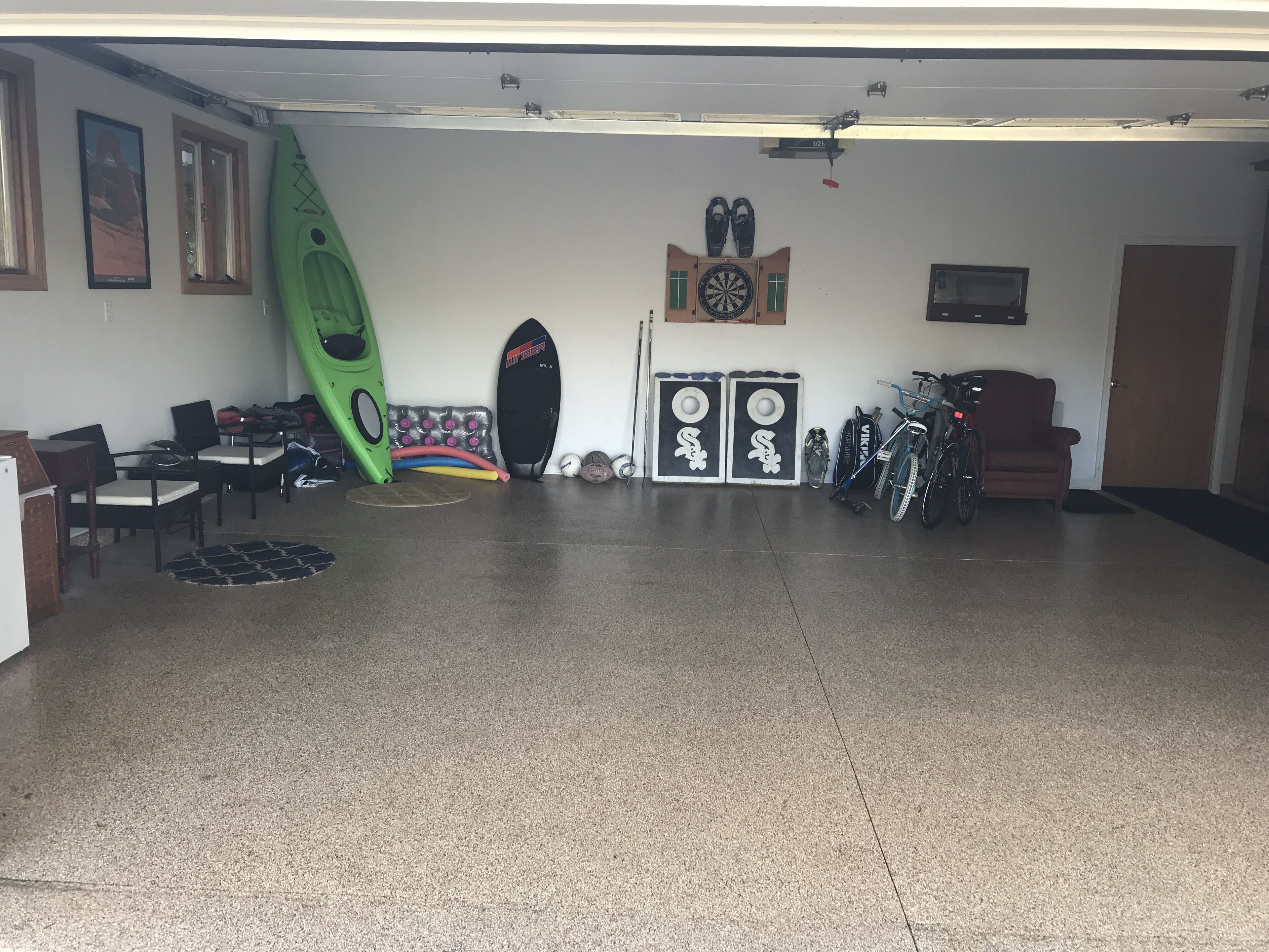 Een garage met een kajak, surfplanken en een fiets.