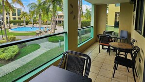Un balcon avec vue sur la piscine, un espace salon extérieur et un ciel dégagé.
