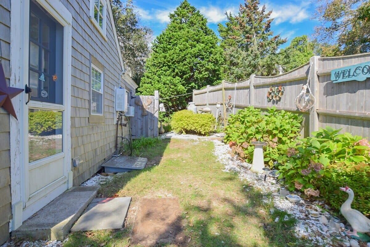 A backyard with a wooden fence, a welcome sign, and a bird bath.