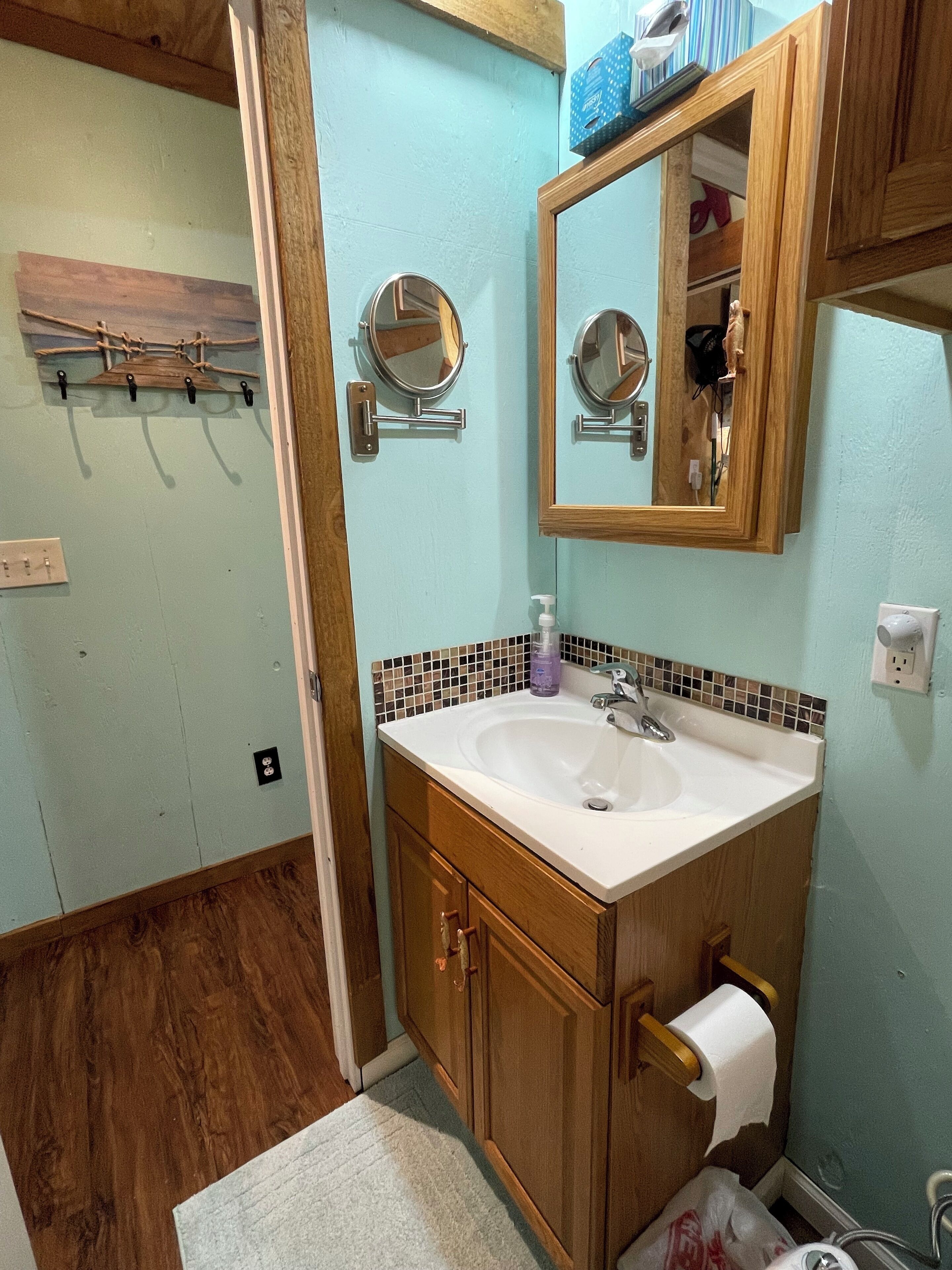 A bathroom with a wooden vanity, two mirrors, a sink, and a towel rack.