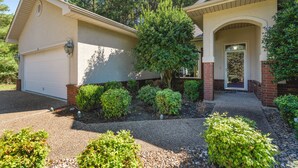 A residential house with a garage, a covered porch, and a landscaped front yard with various shrubs and trees. - Awesome Decorated Lovely, Spacious Townhome by Isabella Golf Course!   (Hot Springs Village)