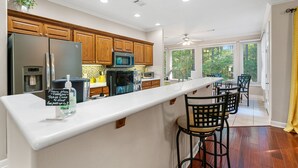 A modern kitchen with wooden cabinets, stainless steel appliances, and a bar area with stools. - Awesome Decorated Lovely, Spacious Townhome by Isabella Golf Course!   (Hot Springs Village)