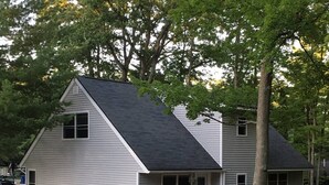 Une maison à deux étages avec une terrasse à l’avant et un petit porche.