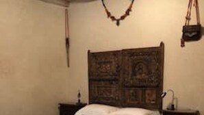 A bedroom with a wooden headboard, a bed with a white bedspread, a nightstand, and a patterned rug.
