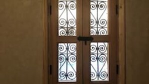 A wooden-framed window with decorative iron bars.