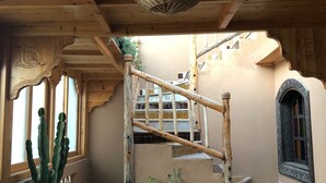 Un intérieur en bois avec un sol à carreaux, un escalier et diverses plantes en pot.