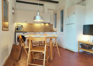 A compact kitchen with a dining table and chairs, a microwave, a sink, and a refrigerator.