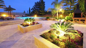 A pool area with lounge chairs, a barbecue grill, and decorative lighting. - SON LLANERAS VILLA - NEAR ES TRENC, MALLORCA, RELAXING GETAWAY, POOL, A/C, WIFI (Campos)