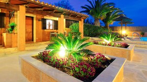 A well-lit outdoor area with a pool, palm trees, and a building with a tiled roof. - SON LLANERAS VILLA - NEAR ES TRENC, MALLORCA, RELAXING GETAWAY, POOL, A/C, WIFI (Campos)