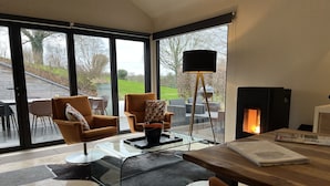 Un salon moderne avec une table en verre, un pouf en cuir et une cheminée.