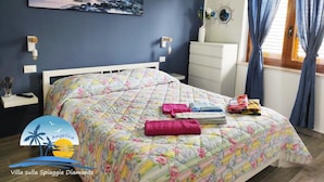 A bedroom with a bed, a nightstand, a dresser, a painting, and a window with curtains. - Villa on the Diamante beach  (Belvedere Marittimo)
