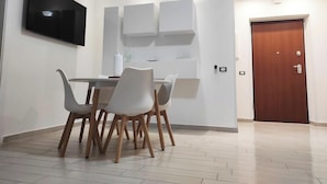 A modern dining area with a table and chairs, a flat-screen TV mounted on the wall, and a wooden door. - Villa on the Diamante beach  (Belvedere Marittimo)