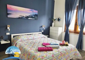 Un dormitorio con una cama, una mesita de noche, un aparador, un cuadro y una ventana con cortinas.