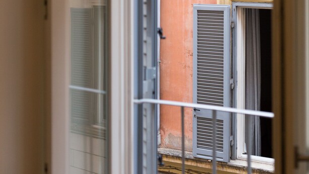 An open door leading to a balcony with a view of a building with shutters and a tiled wall. - Luxury apartment in the heart of Rome - Spanish Steps, wi-fi, a / c, (Roma)