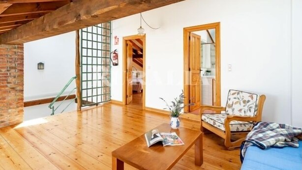 Un ampio loft con pavimenti in legno, una panca di legno, un divano e una scala.