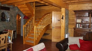 A wooden interior with a staircase, a fireplace, a bookshelf, and a leather sofa. - Chalet in wood and stone, redone, 250 metres from the ski lifts. (Les Deux-Alpes)