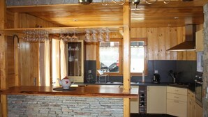 A kitchen with wooden cabinets, a stone backsplash, and a countertop with a teapot and glasses. - Chalet in wood and stone, redone, 250 metres from the ski lifts. (Les Deux-Alpes)