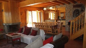 A cozy cabin interior with a fireplace, wooden furniture, a dining area, and a stone wall. - Chalet in wood and stone, redone, 250 metres from the ski lifts. (Les Deux-Alpes)