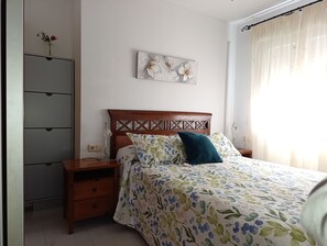 A bedroom with a wooden headboard, a floral bedspread, and a nightstand with a lamp.