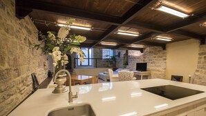A modern kitchen with a large island, a built-in sink, and a stone wall backdrop. - Loft in the center of Assisi (Assisi)