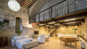 A rustic interior with stone walls, a wooden ceiling, a bed, a sofa, a dining table, and a staircase. - Loft in the center of Assisi (Assisi)