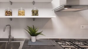 Een moderne keuken met witte planken, een gasfornuis en een spoelbak.