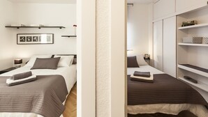 Een moderne hotelkamer met twee bedden, een grote garderobe en een plank met decoratieve voorwerpen.