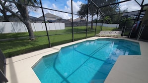 A swimming pool with a clear view of the surrounding area, including a white fence, a lawn, and a house in the background. - HUGE 5 Bedroom highly rated pool villa Star wars cinema, games room, Disney room (davenport)