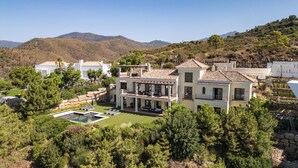 Une vaste villa moderne dotée d’une piscine, entourée d’une végétation luxuriante et avec des montagnes en toile de fond.