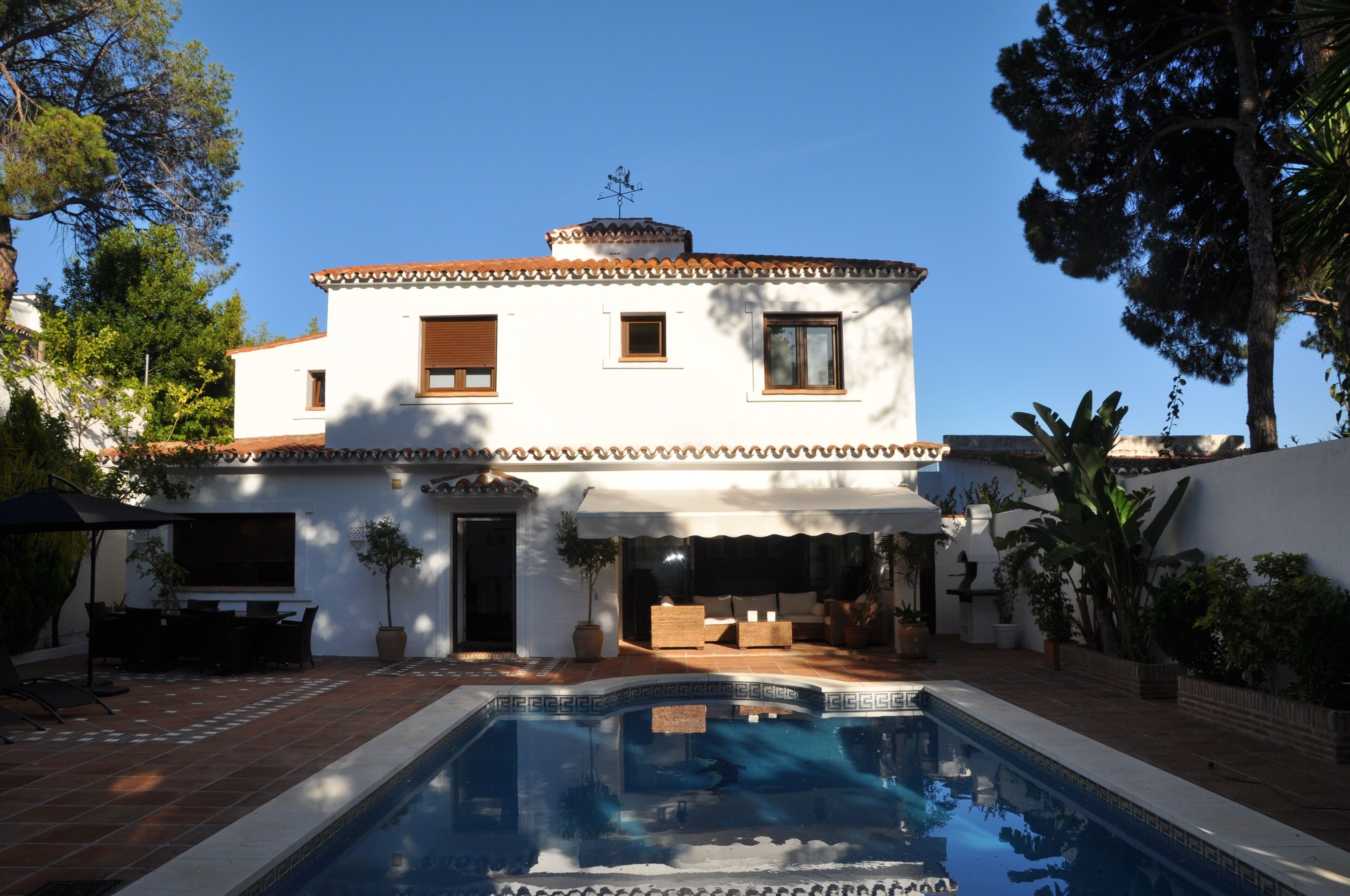 Une maison à deux étages avec une piscine en premier plan.