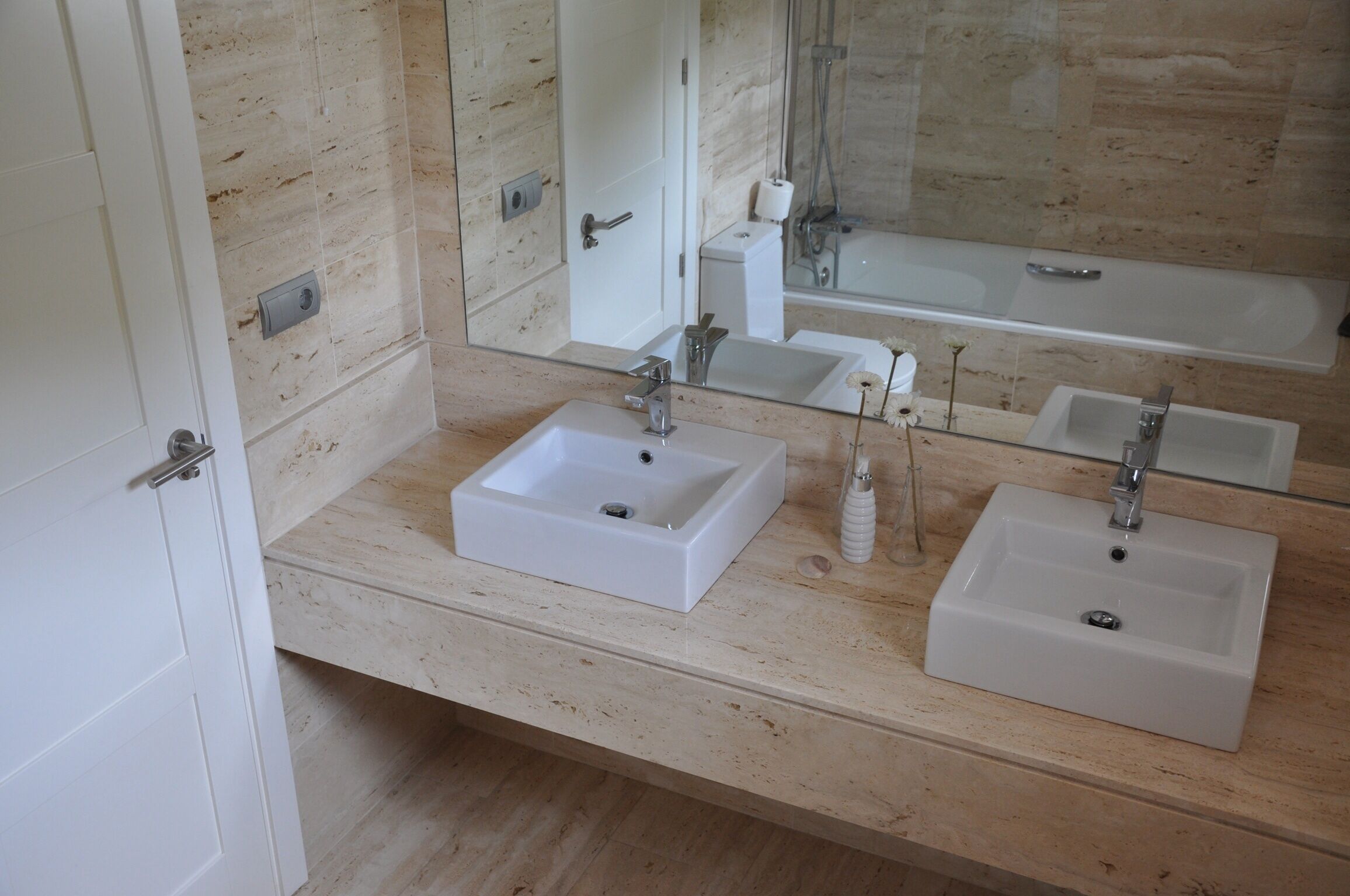 A bathroom with two sinks, a mirror, and a bathtub.