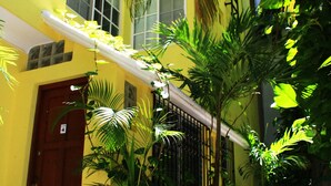 A yellow building with a red door, large windows, and potted plants. - Cozy Studio for 2 pers. near 5th avenue (Playa del Carmen)