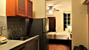 A compact kitchen with a sink, a refrigerator, and wooden cabinets. - Cozy Studio for 2 pers. near 5th avenue (Playa del Carmen)