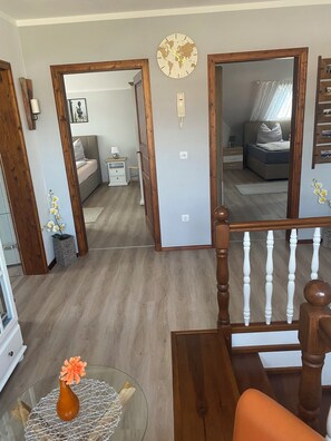 A room with a bed, bedside table, and a mirror. There is a wooden staircase with a railing.