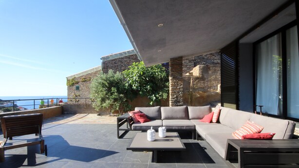 A modern outdoor patio with a sofa, coffee table, and bench, overlooking a scenic view.