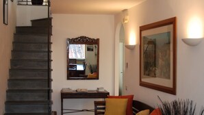 A staircase leading to a landing with a desk and chair, a sofa with cushions, and a framed picture on the wall. - Beautiful Lucchese Apartment with Stunning Views (Lucca)