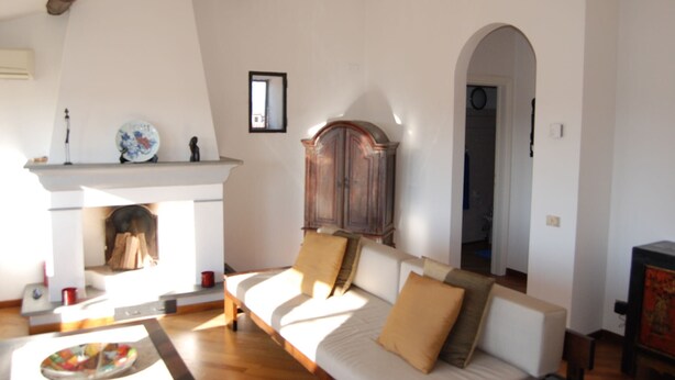 A living room with a fireplace, a sofa, and a wooden cabinet. - Beautiful Lucchese Apartment with Stunning Views (Lucca)