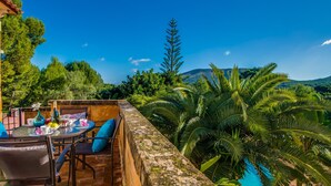 A terrace with a table and chairs, overlooking a pool and lush greenery. - Apartment beach Sol de Mallorca 2 with pool (Cala Mesquida)
