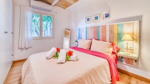 A bedroom with a bed, a window with curtains, a bedside table with a lamp, and a wall with framed pictures. - Apartment beach Sol de Mallorca 2 with pool (Cala Mesquida)