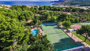 An aerial view of a coastal area with a tennis court, a swimming pool, and lush greenery. - Apartment beach Sol de Mallorca 2 with pool (Cala Mesquida)
