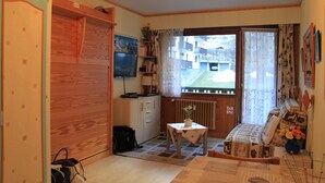 A compact living space with a kitchenette, a dining area, and a window with a view of buildings outside. - CHAMONIX superb stud 2/3 pers, private residence, parking, ski lift access (Chamonix-Mont-Blanc)