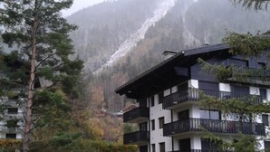 A multi-story building with balconies, surrounded by trees and a mountain backdrop. - CHAMONIX superb stud 2/3 pers, private residence, parking, ski lift access (Chamonix-Mont-Blanc)