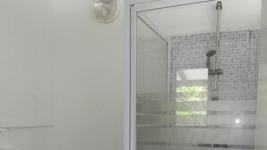 A bathroom with a toilet, a shower enclosure, and a toilet paper holder.