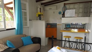 A cozy room with a bed, a sofa, and a small kitchenette.