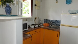 A compact kitchen with a microwave, gas stove, sink, and a refrigerator.