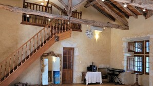 Une pièce spacieuse avec un escalier en bois, un piano et une cheminée.